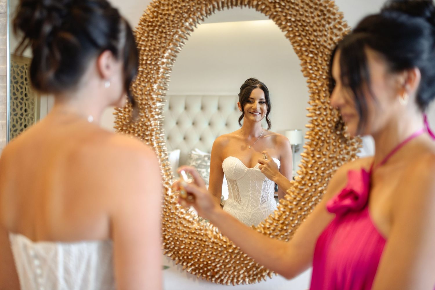 Wedding party getting ready in front of an ornate gold-framed mirror.