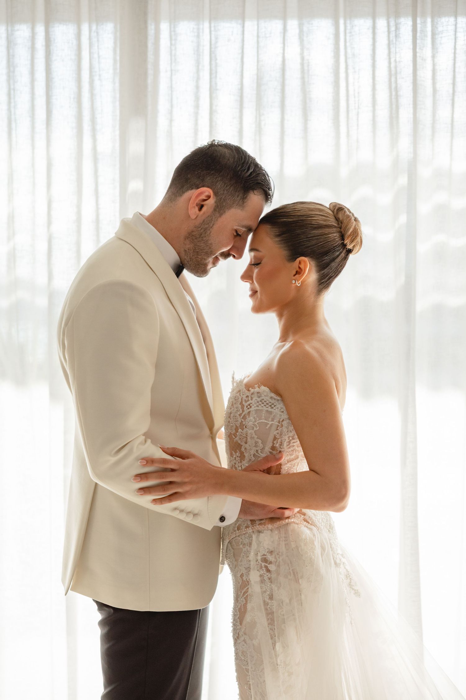 Intimate wedding portraits showing sweet interactions between newlyweds in a bright room.