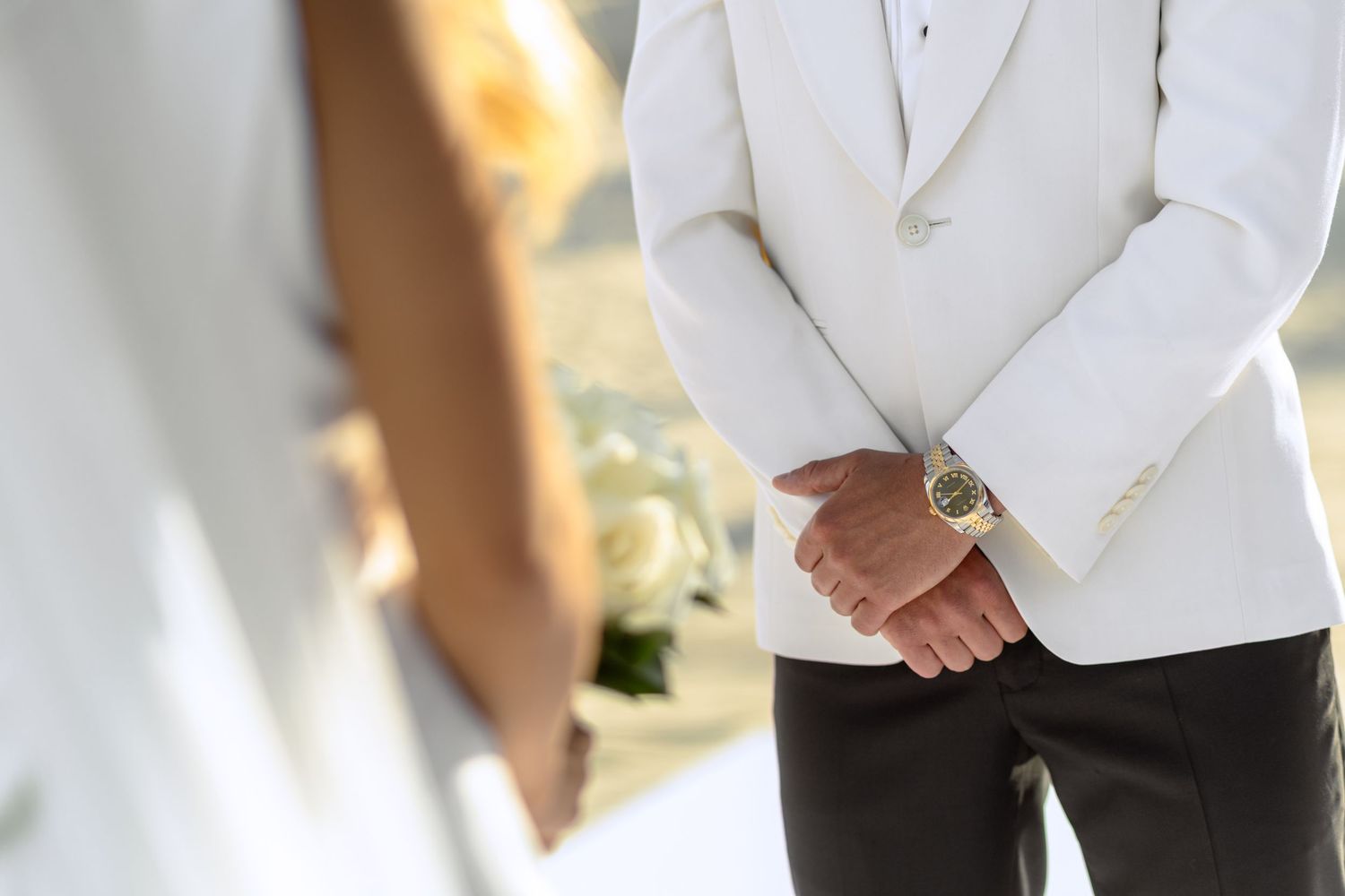 Partial view of couple in formal white wedding attire at beach ceremony.