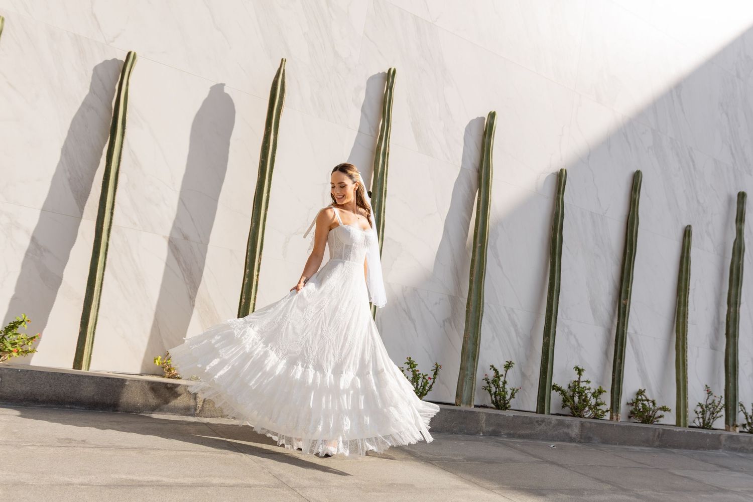 White wedding dress photographed against minimalist white wall with architectural elements.
