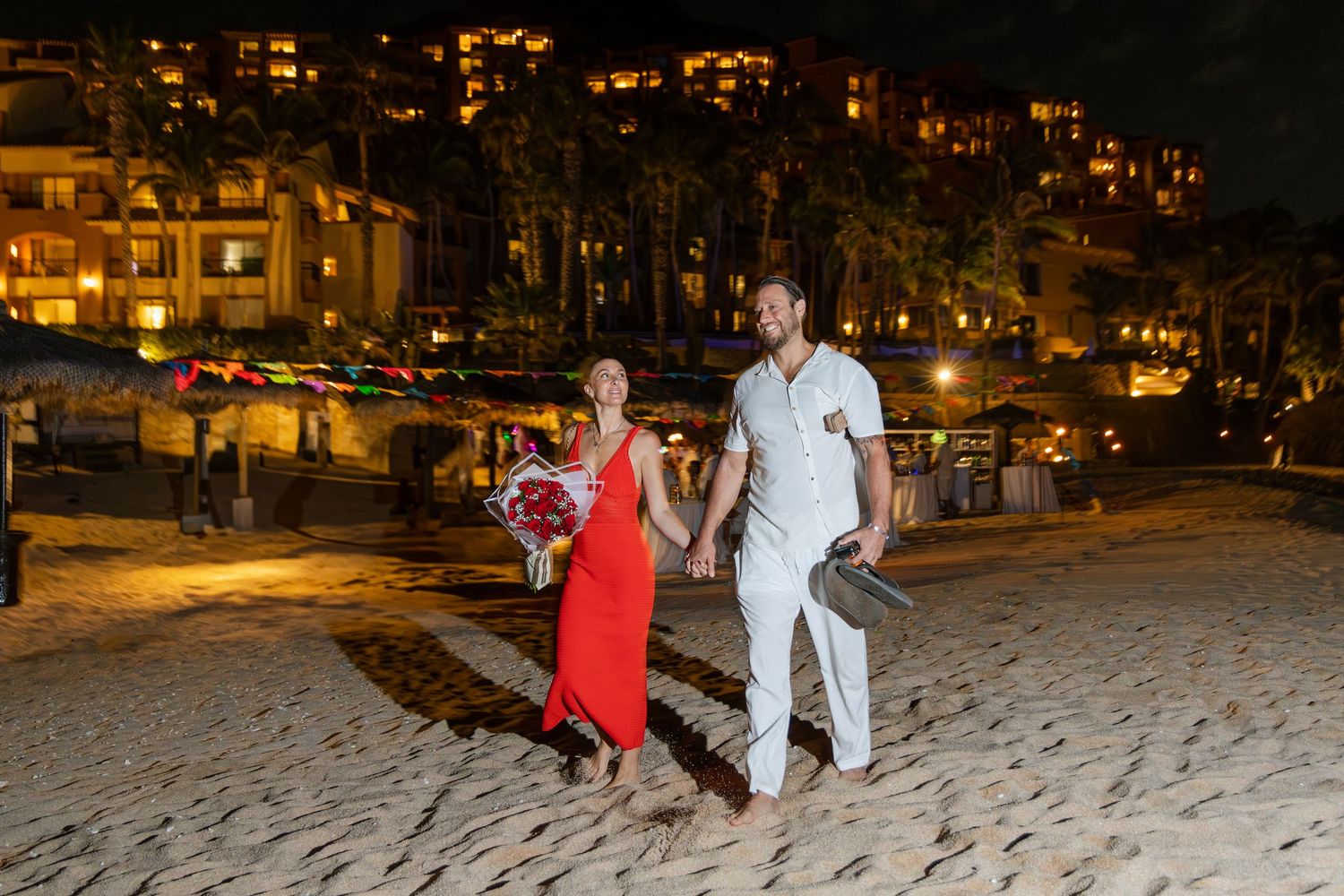 People enjoying a nighttime snowball fight in an illuminated urban park with buildings visible in the background.