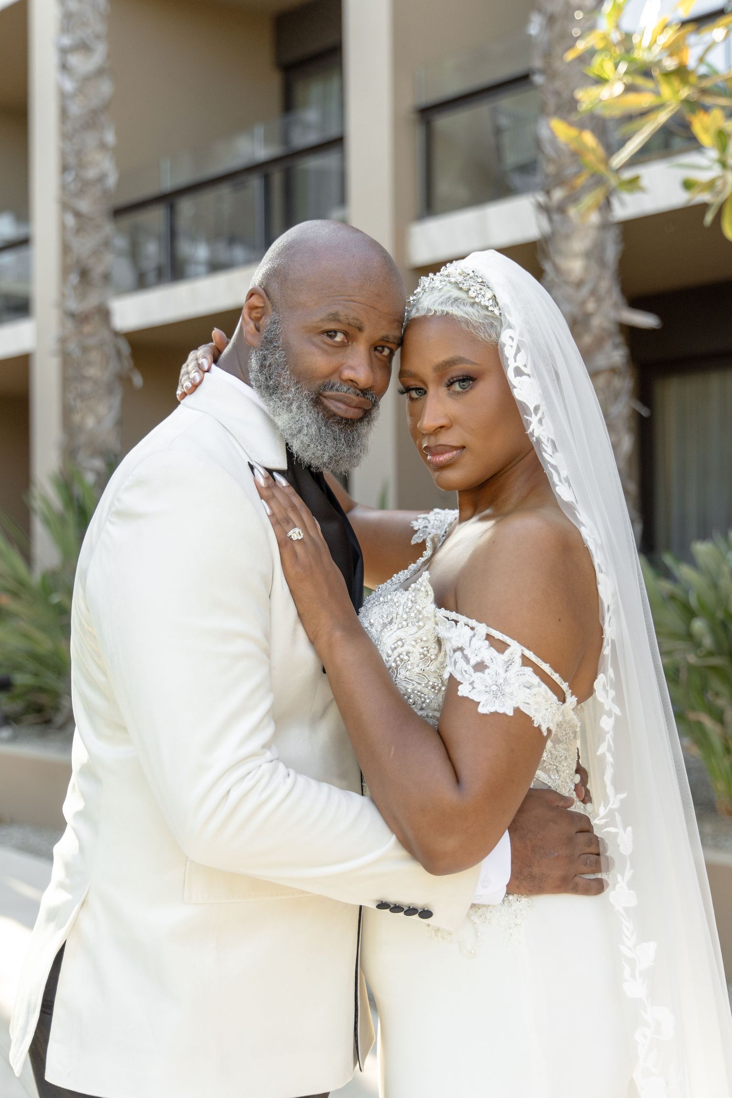 Romantic outdoor portrait of newlyweds embracing in formal wedding attire.