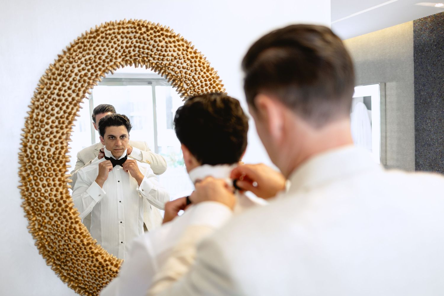 Wedding party getting ready in front of decorative gold circular backdrop.