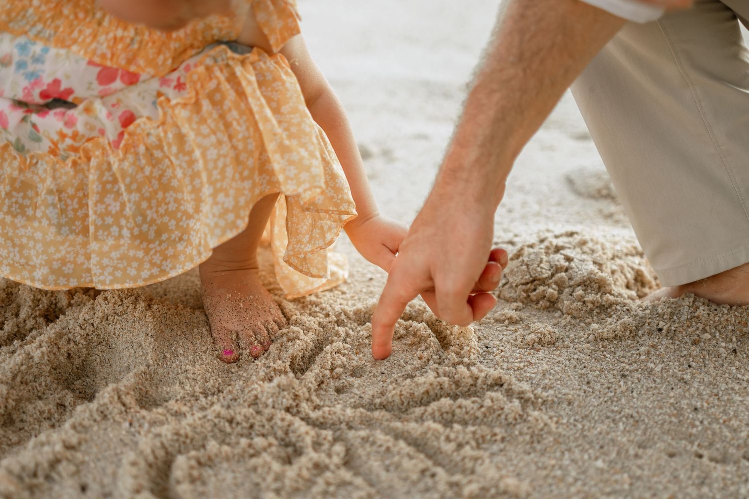 Close-up of hands playing in soft beach sand during a sunny day.