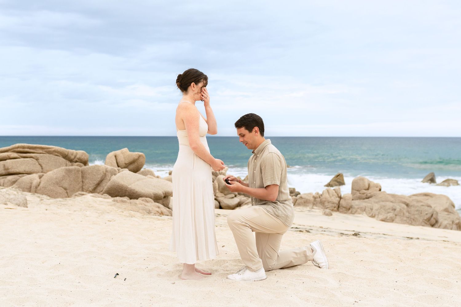 A romantic beach proposal sequence showing a couple on sandy shores with crashing waves in the background.