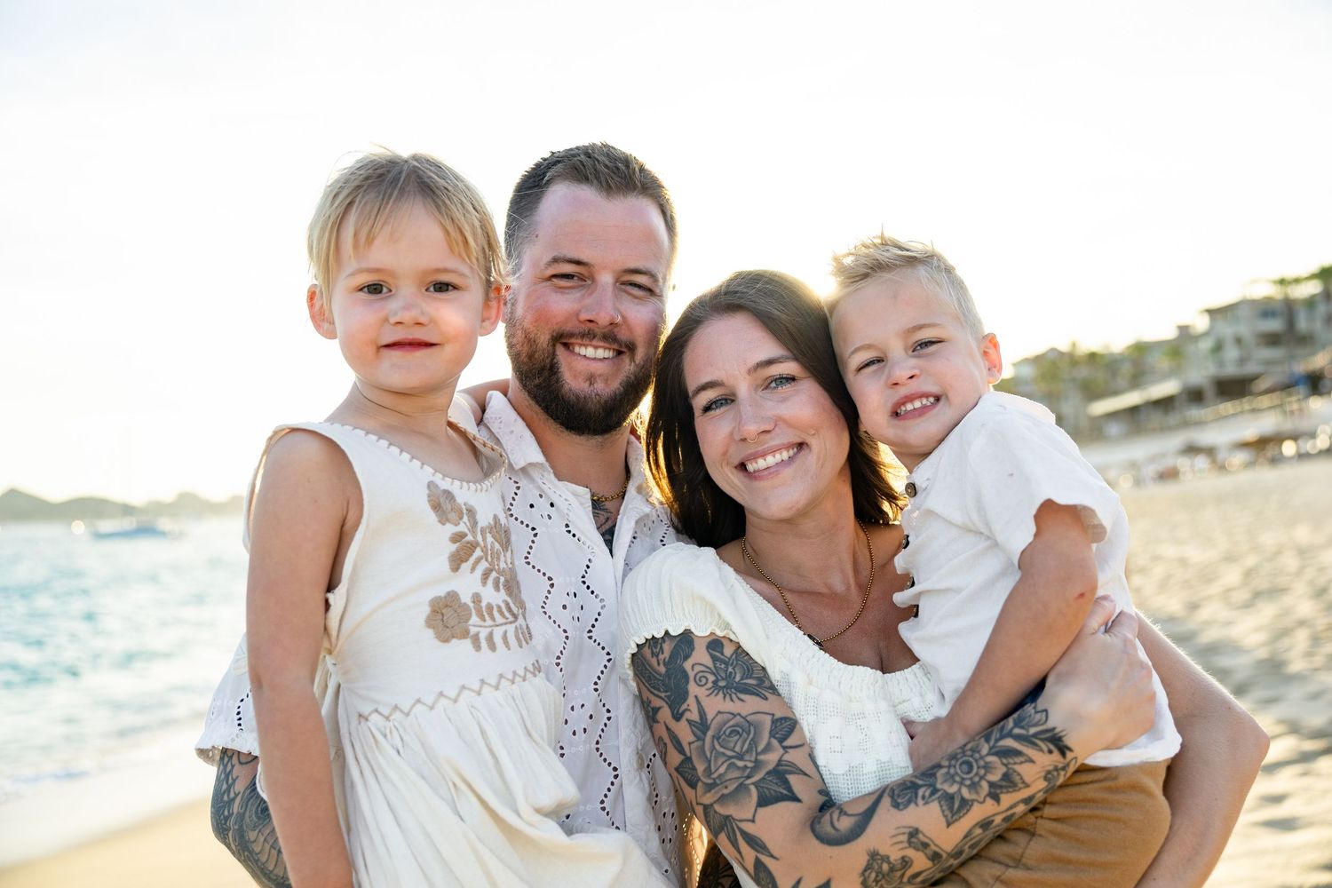 Happy family enjoying a beach photoshoot in cabo san lucas together on a sunny day at the seashore.