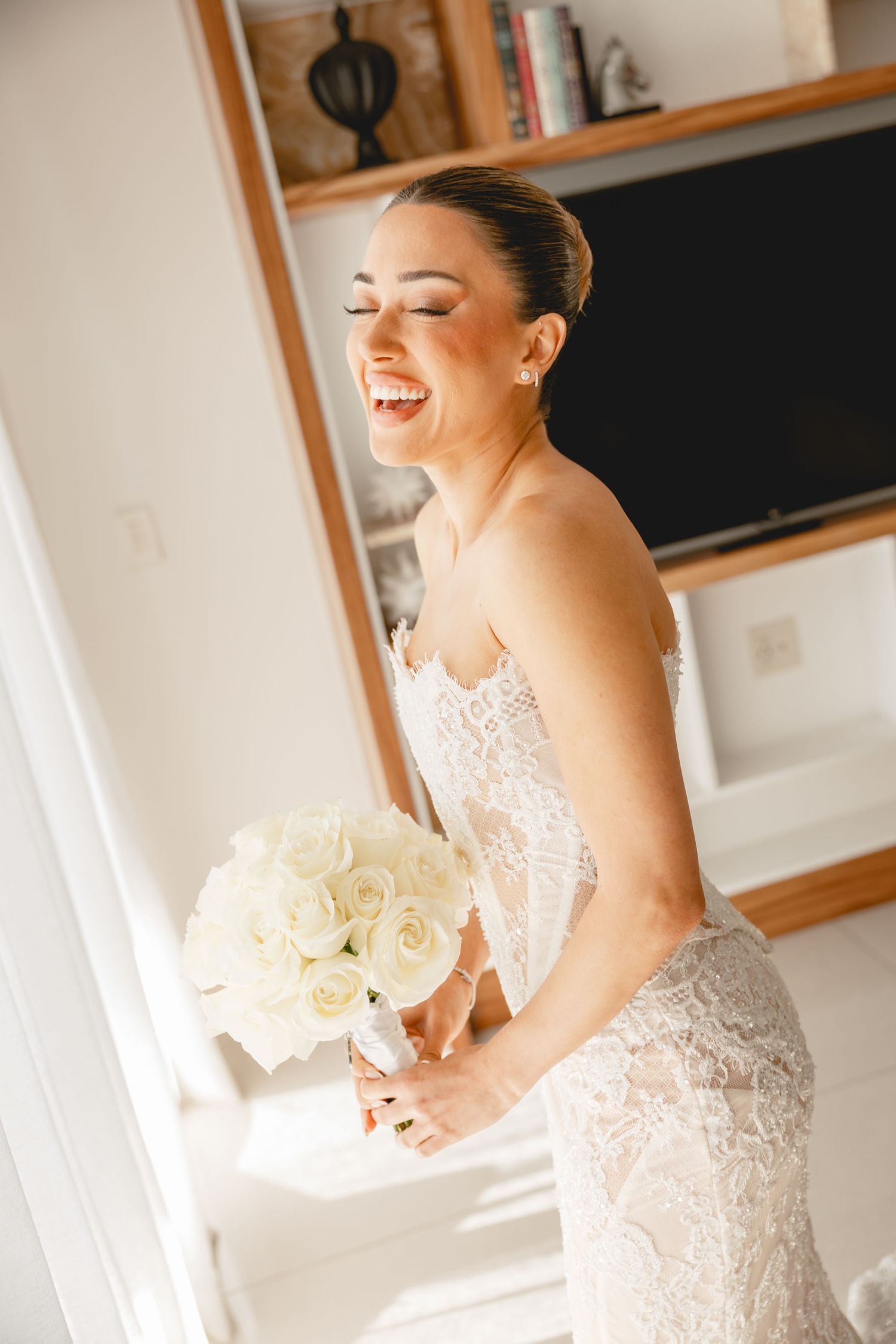 Joyful bridal portrait series with white roses against natural window light.