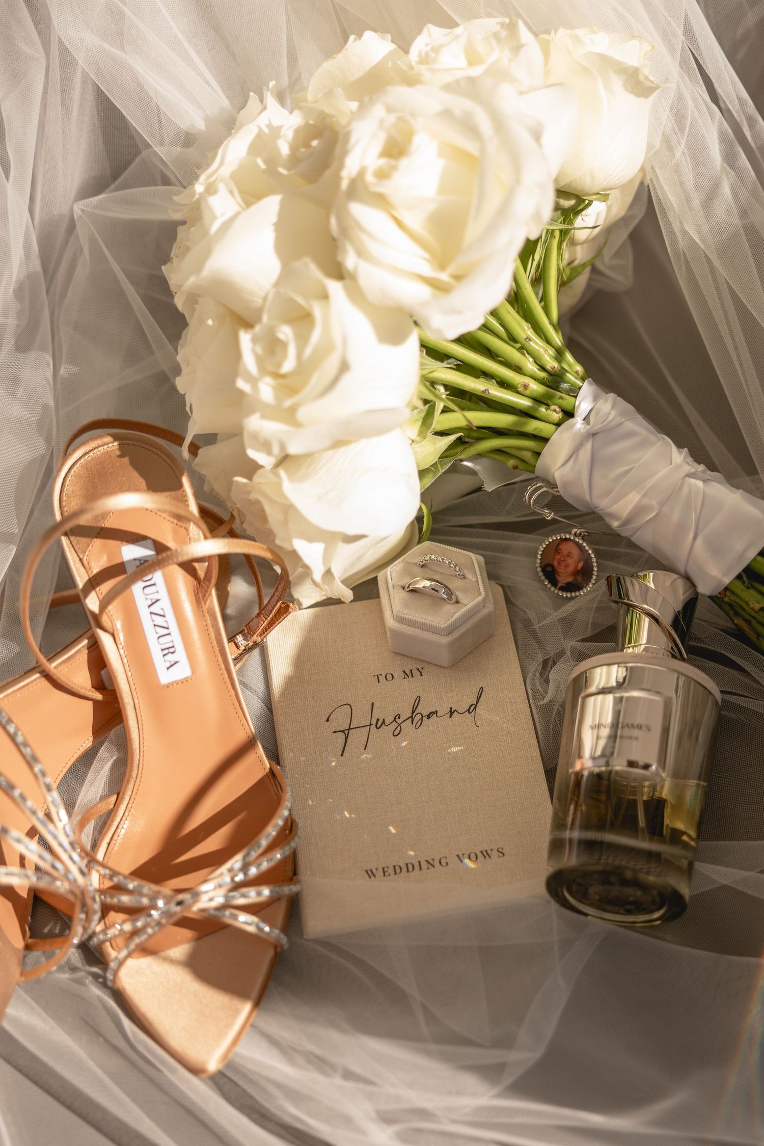 Wedding details including white roses, bridal shoes and vow cards arranged with tulle.