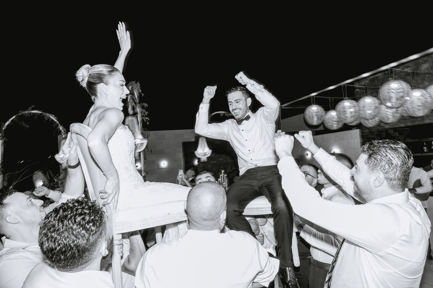 Black and white photo of wedding guests dancing and celebrating on the dance floor.