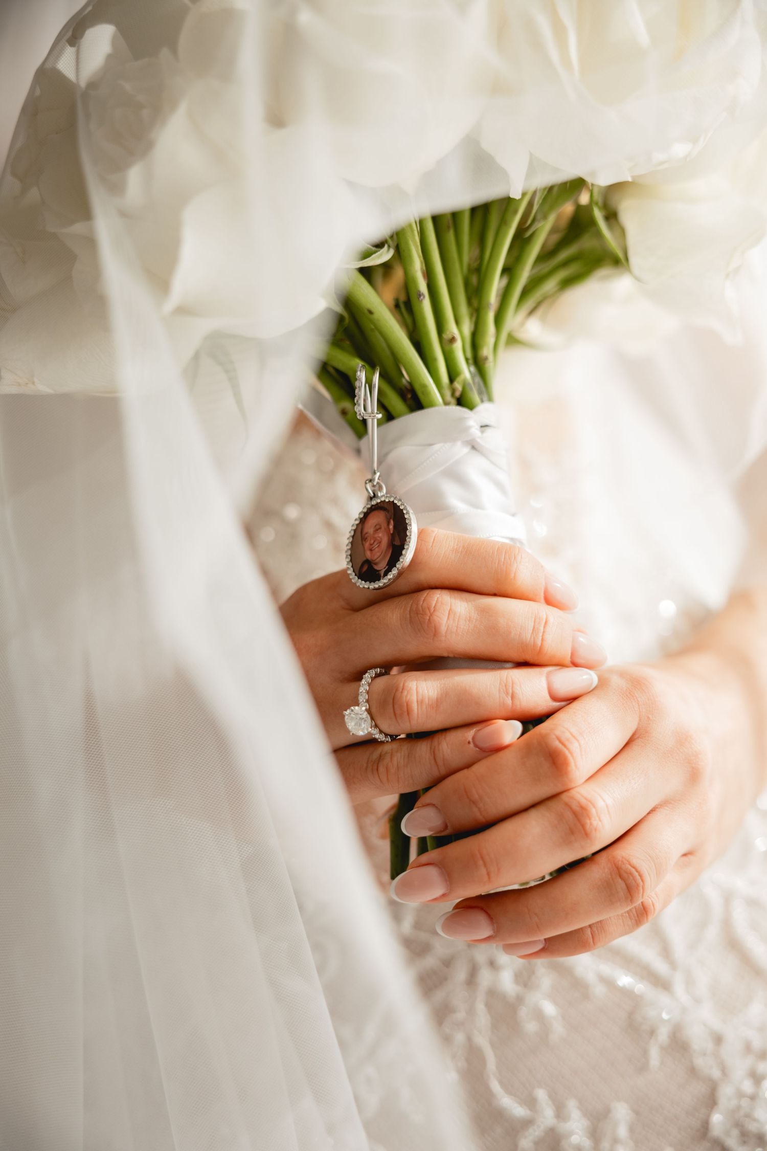 Close-up of hands holding a wedding bouquet with white lace dress details visible.