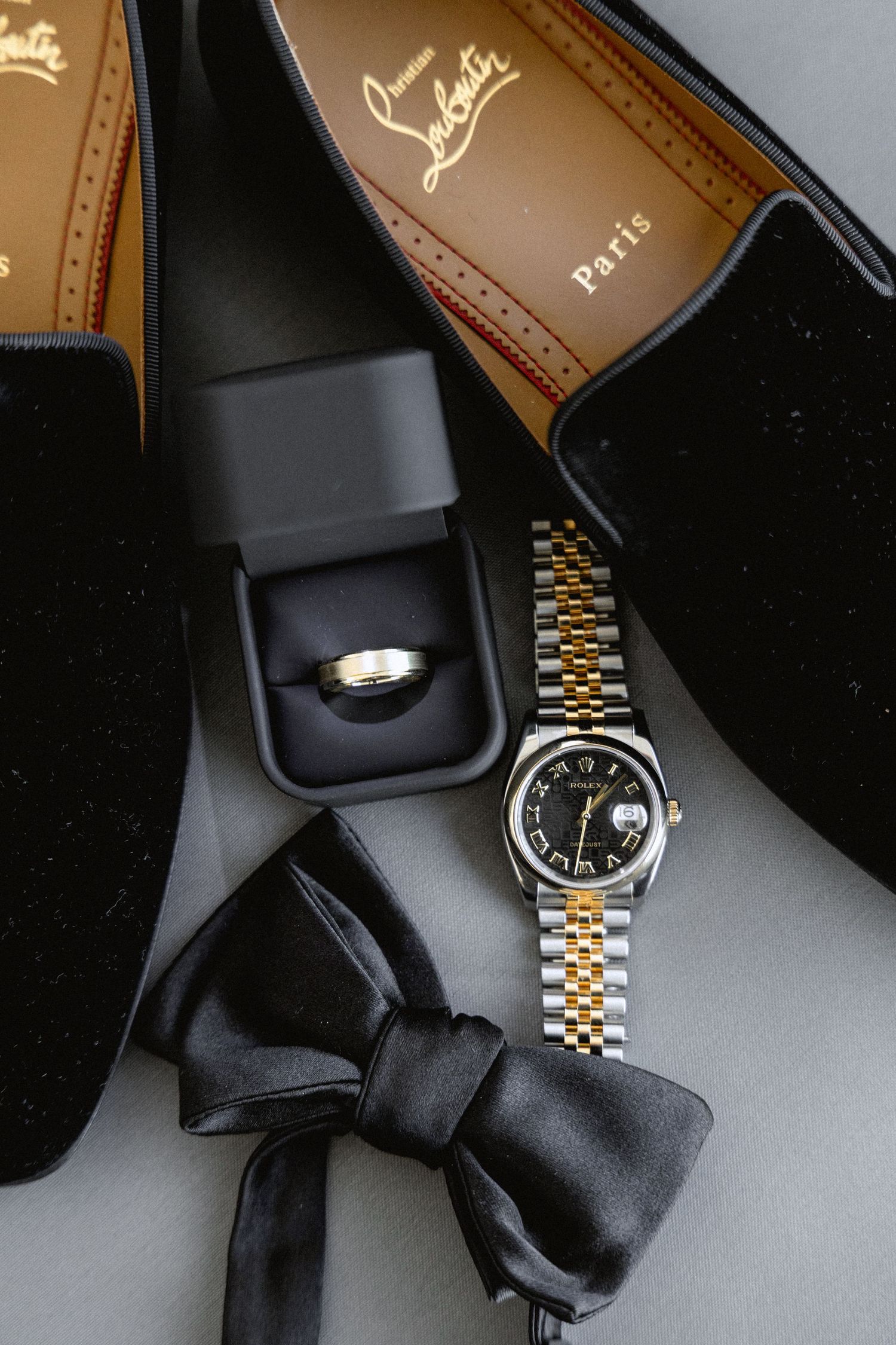 Elegant accessories including a black bow tie and gold watch displayed on a dark surface.