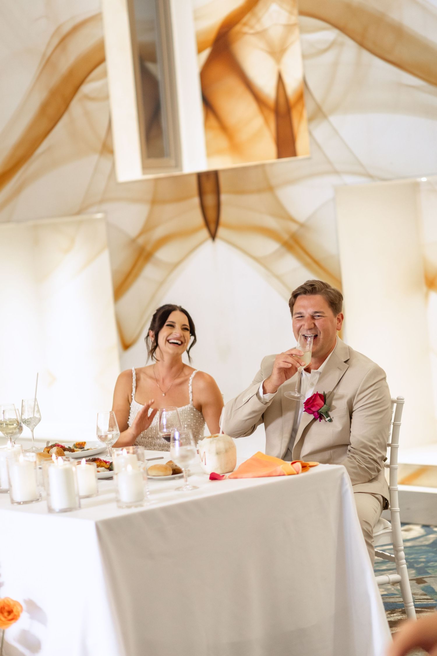Candid moments of laughter shared at the wedding reception head table.