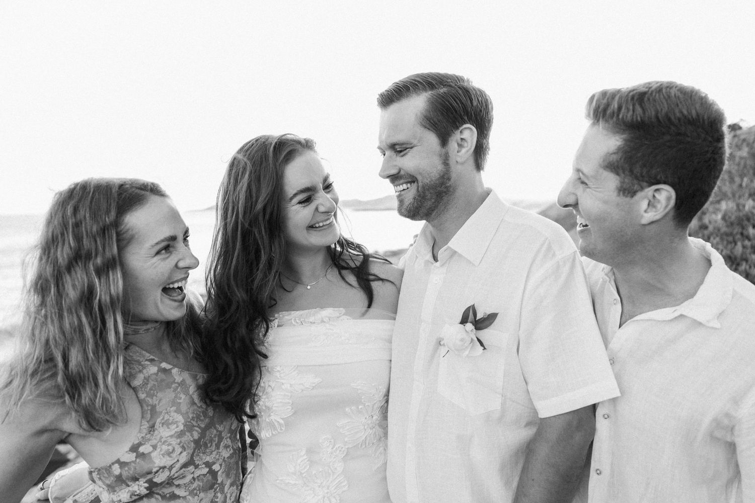 A black and white group photo of friends laughing together outdoors.