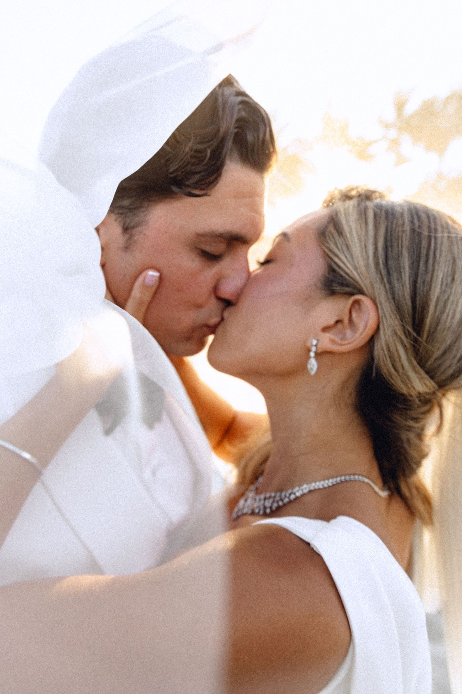 Intimate wedding couple portraits at sunset with bride wearing sparkling jewelry and flowing veil.