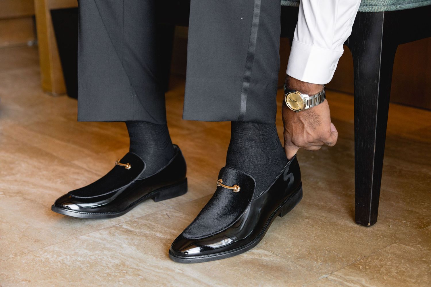 Polished black formal shoes lined up on wooden floor.