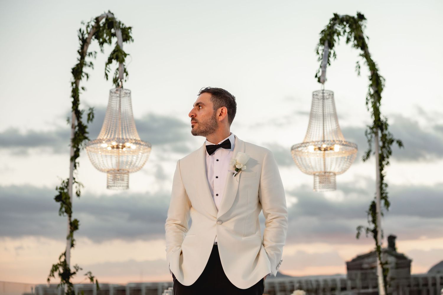 Outdoor wedding ceremony space decorated with hanging greenery and elegant crystal chandeliers.