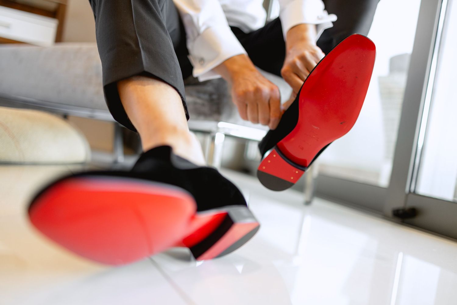 Close-up of red designer shoes being put on before wedding ceremony.