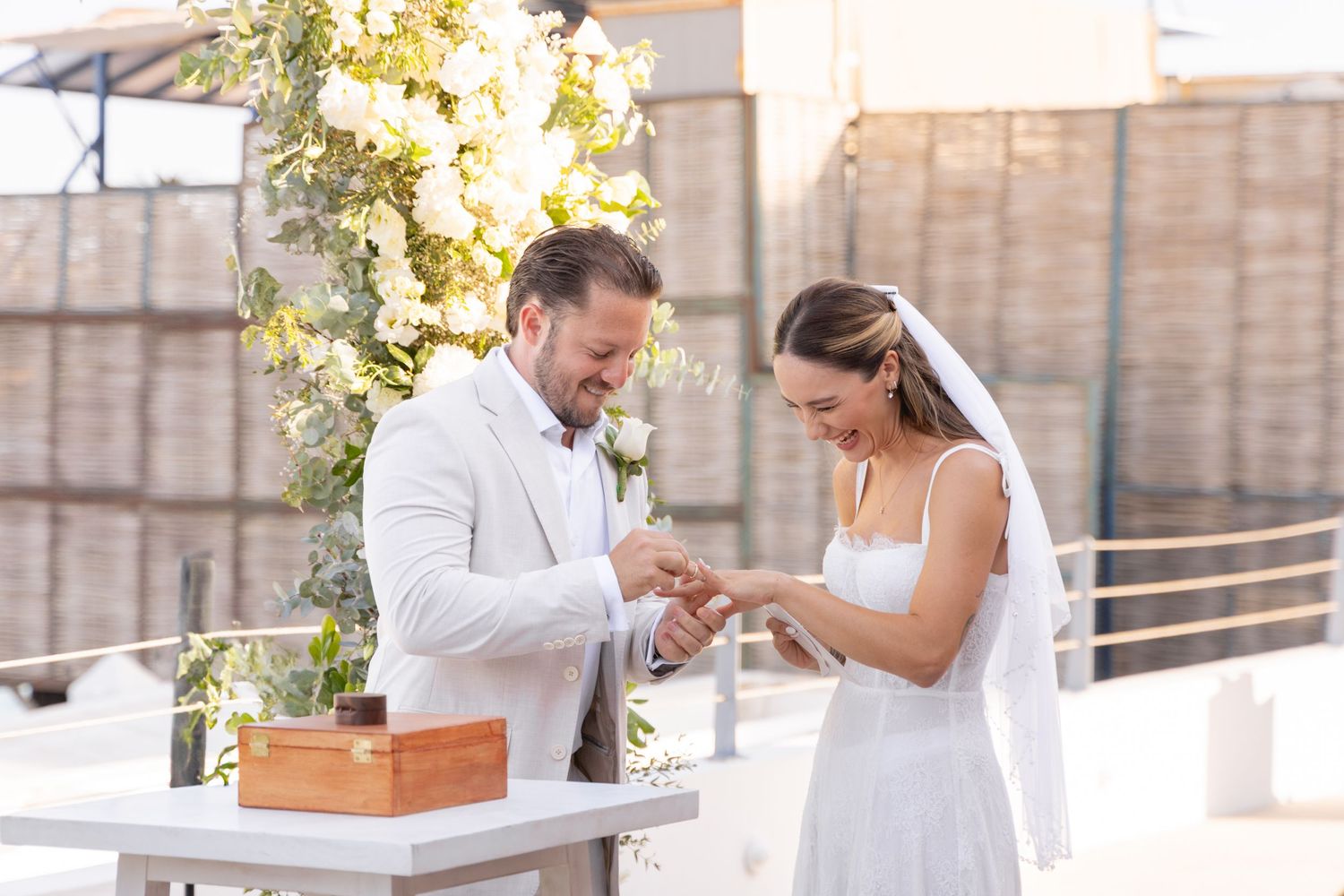 A couple participates in a wedding ritual at a decorated table with a wooden box.