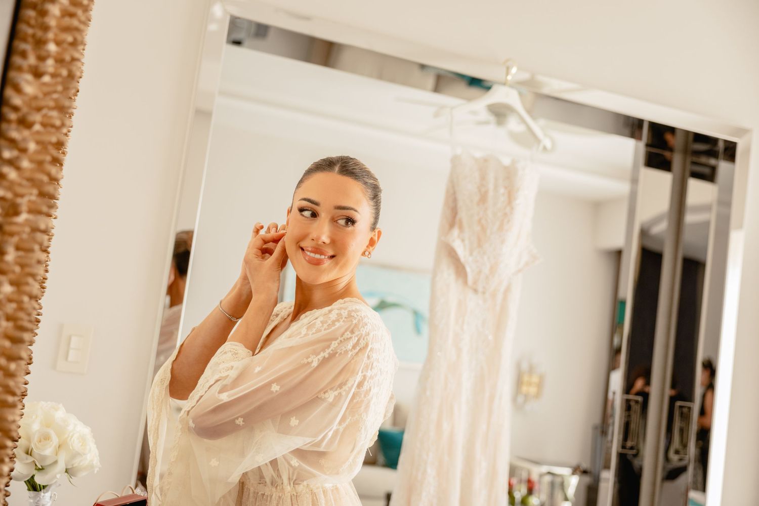 Bride adjusting veil in mirror reflection during wedding preparations.