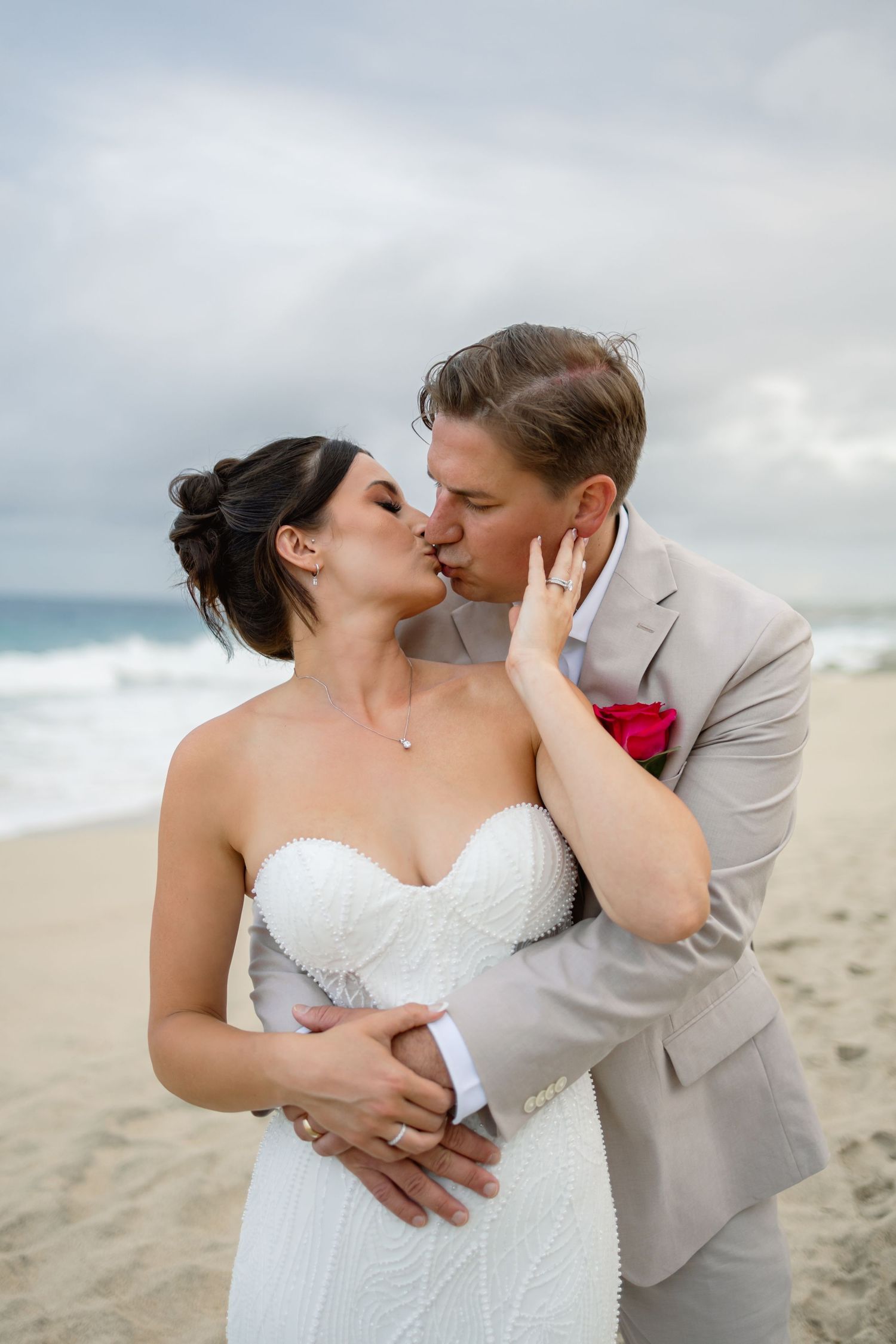 A romantic wedding couple shares intimate moments on a sandy beach.