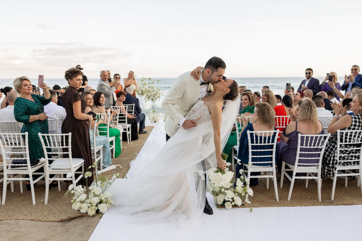 Wedding reception setup with white chairs and ocean view at destination venue.