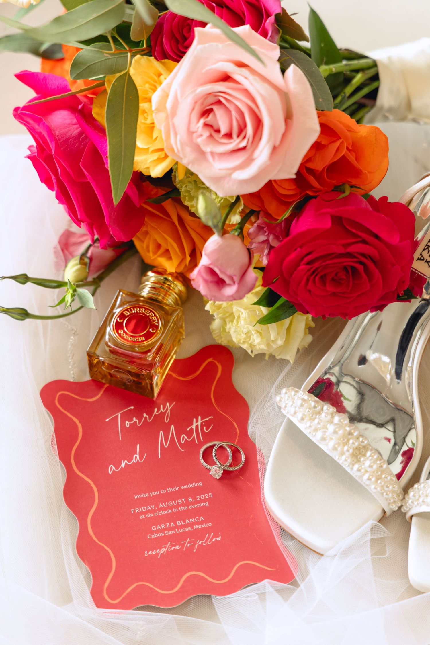 Wedding stationery with red and coral roses, rings and metallic shoes.