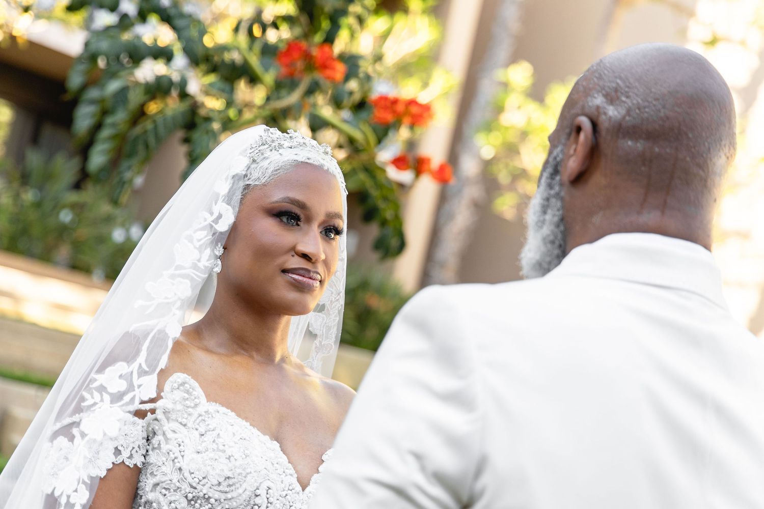 Outdoor wedding ceremony moment with bride in white lace dress and flowing veil.