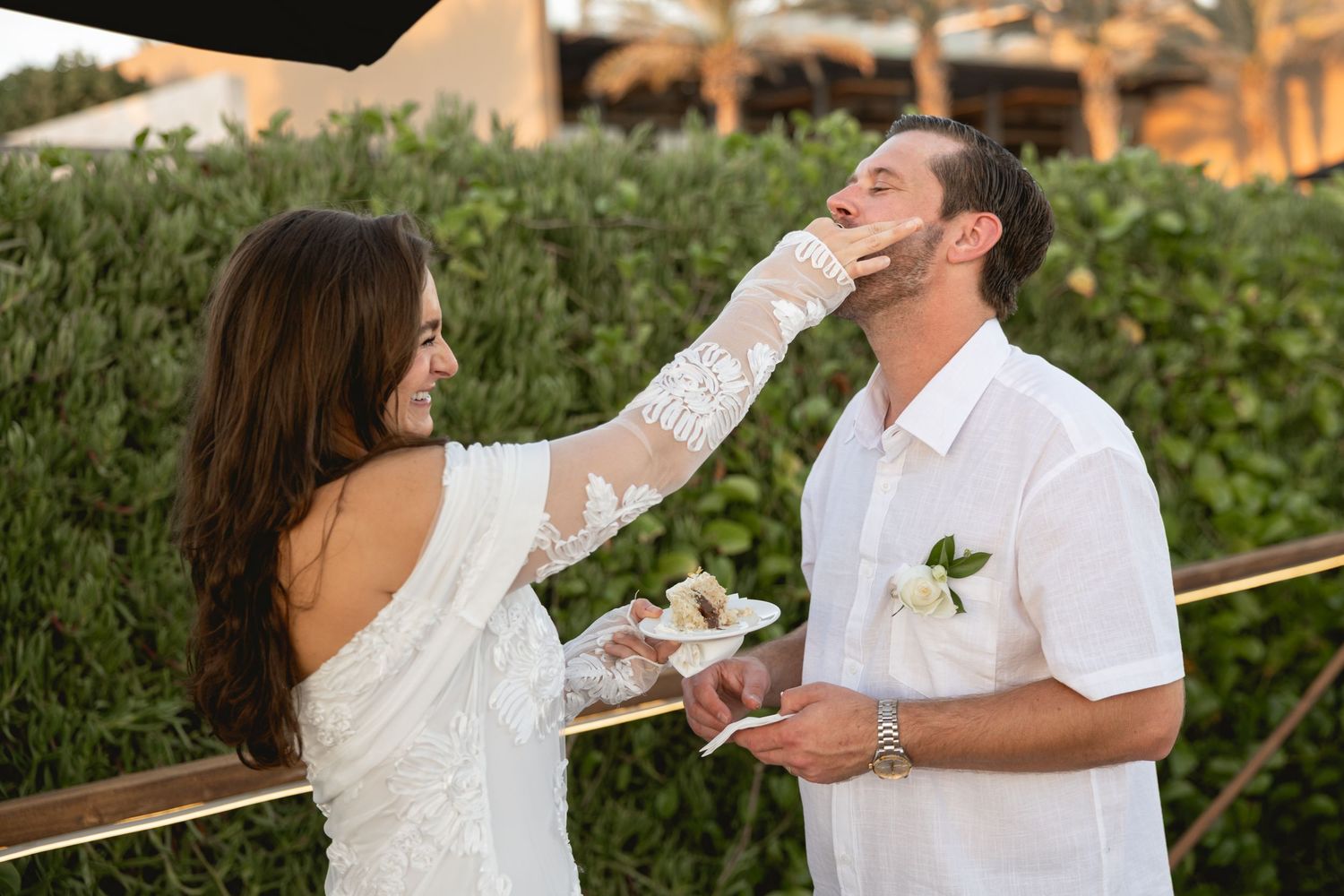 A playful moment during a cake-cutting ceremony at an outdoor celebration.