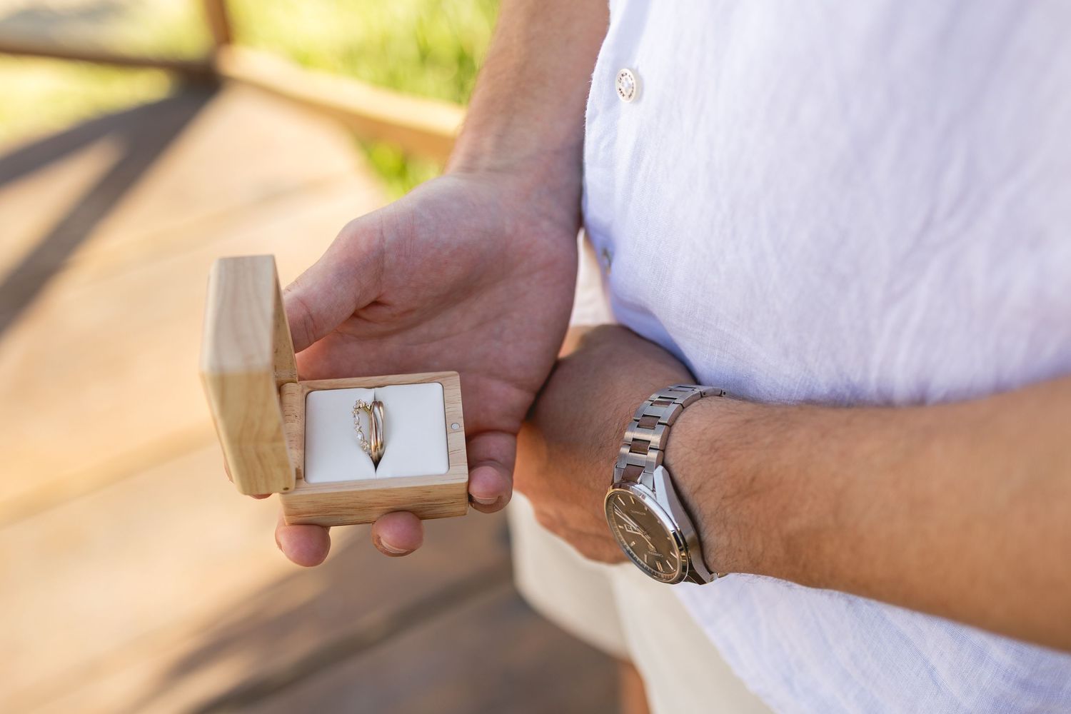 Wedding rings being exchanged between hands wearing white clothing.