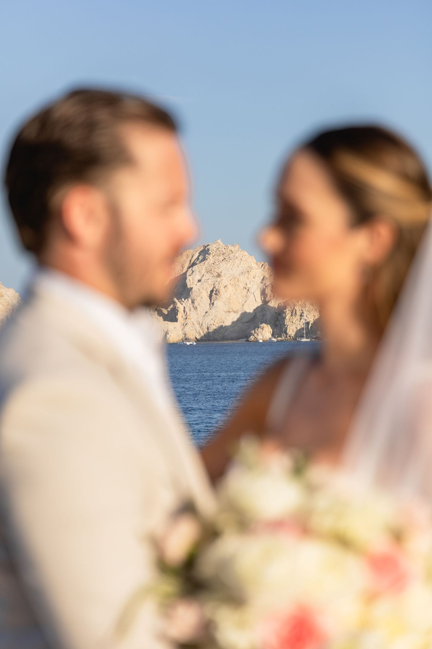 Romantic wedding couple with blurred rock formation in background by the ocean.