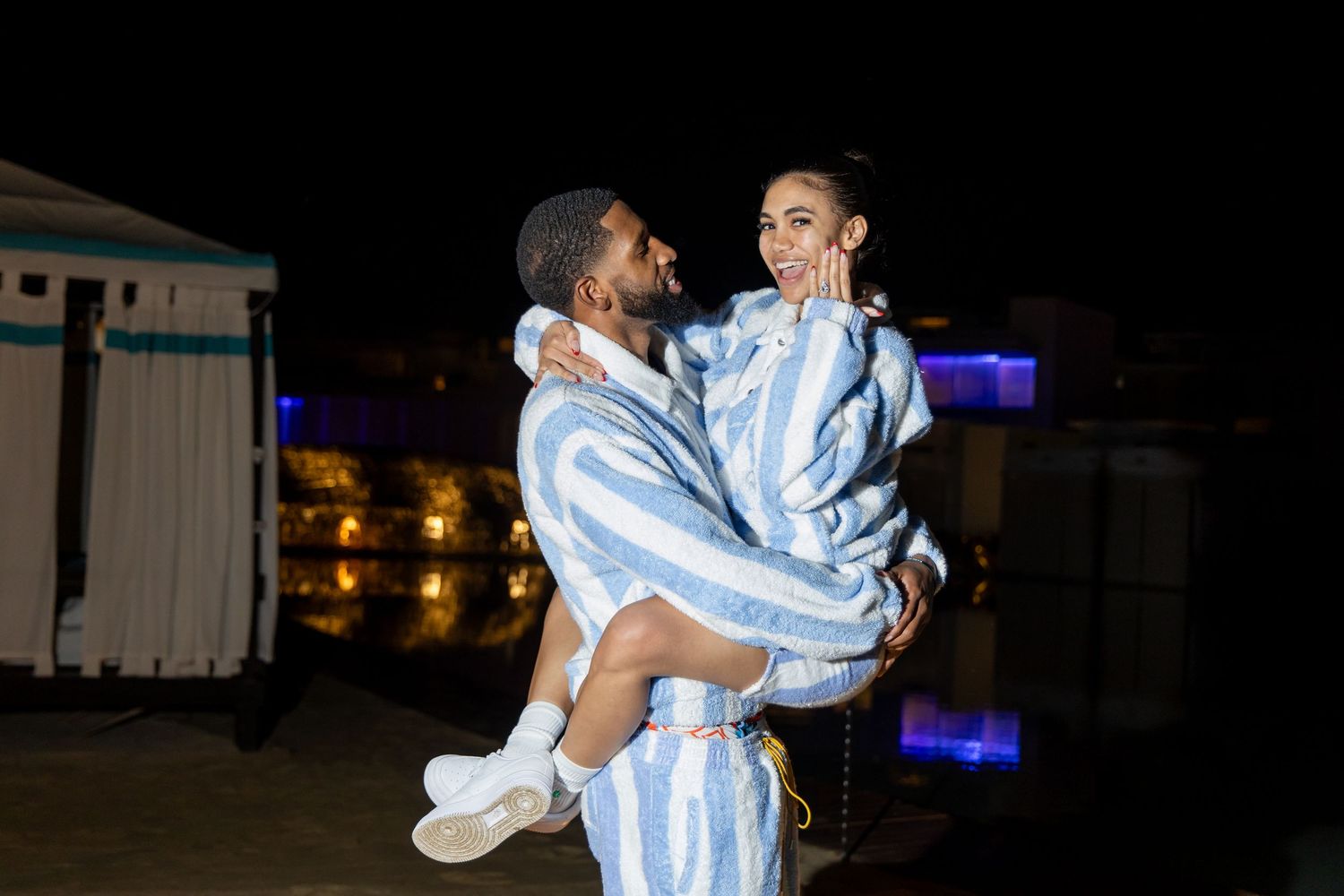 Two people dance together wearing matching striped outfits during a nighttime performance.