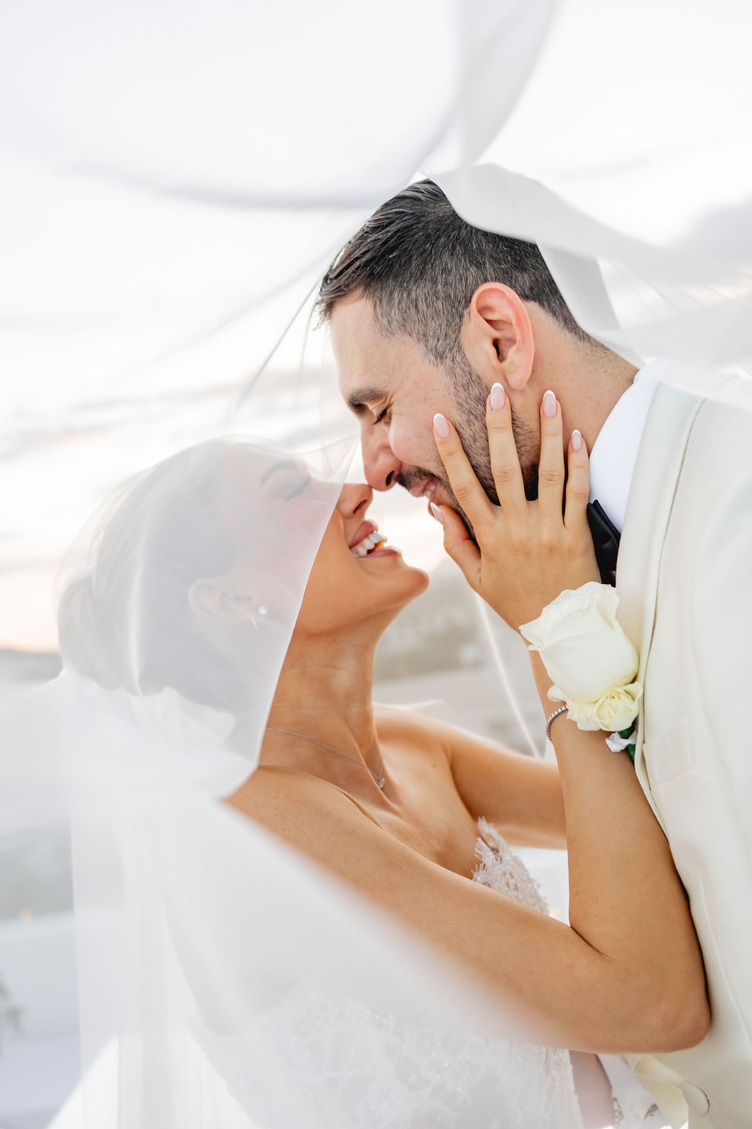 Intimate close-up portrait of a couple in white formal attire sharing a tender moment.