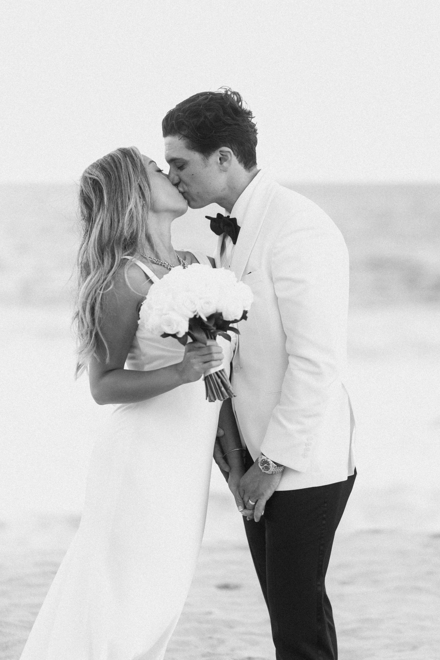 Romantic black and white beach wedding portraits with white floral bouquet.