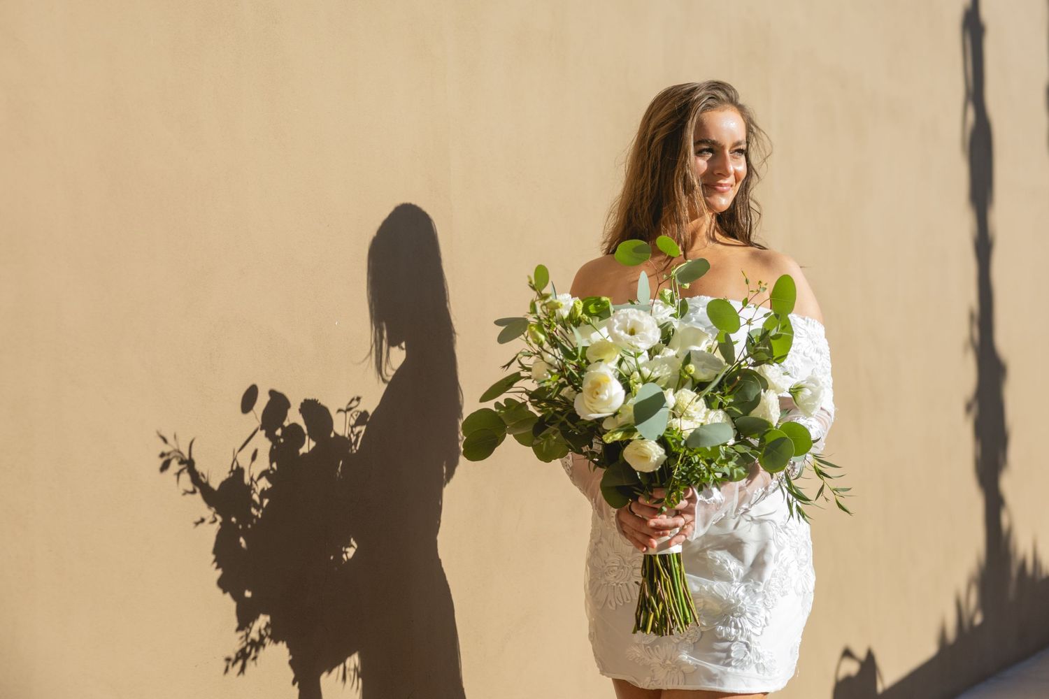 Bridal portrait with dramatic shadows against a beige wall.