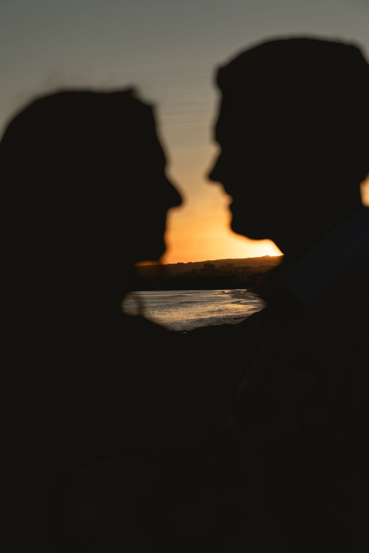 Silhouette of a couple against a sunset ocean backdrop creating a romantic profile.