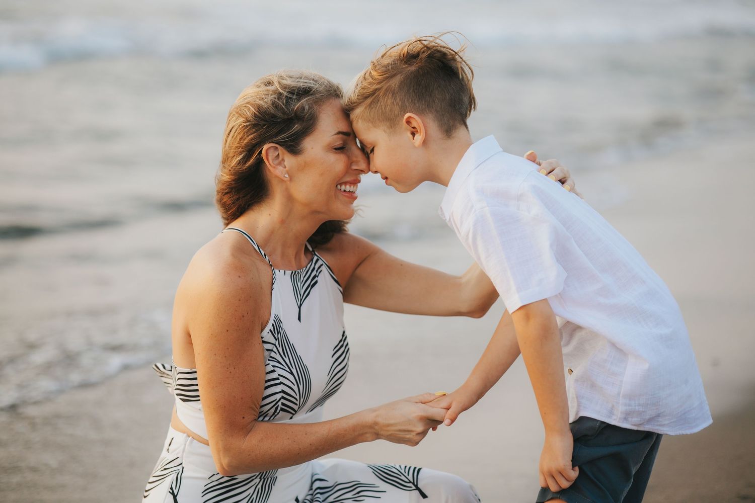 Tender moments shared between family members on a sandy beach at sunset.