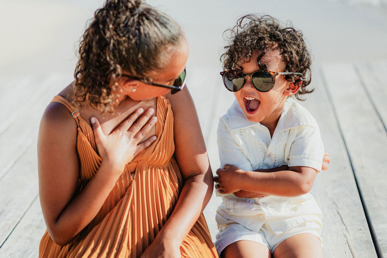 Family shares intimate moments on wooden deck during sunset photoshoot.