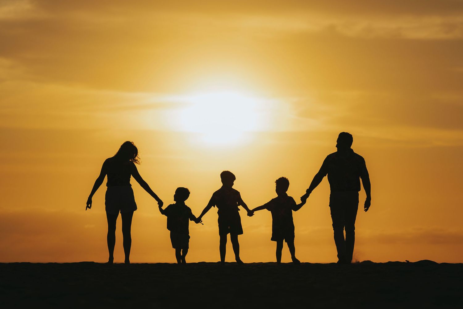 Dramatic silhouettes of people against a vibrant golden sunset sky.