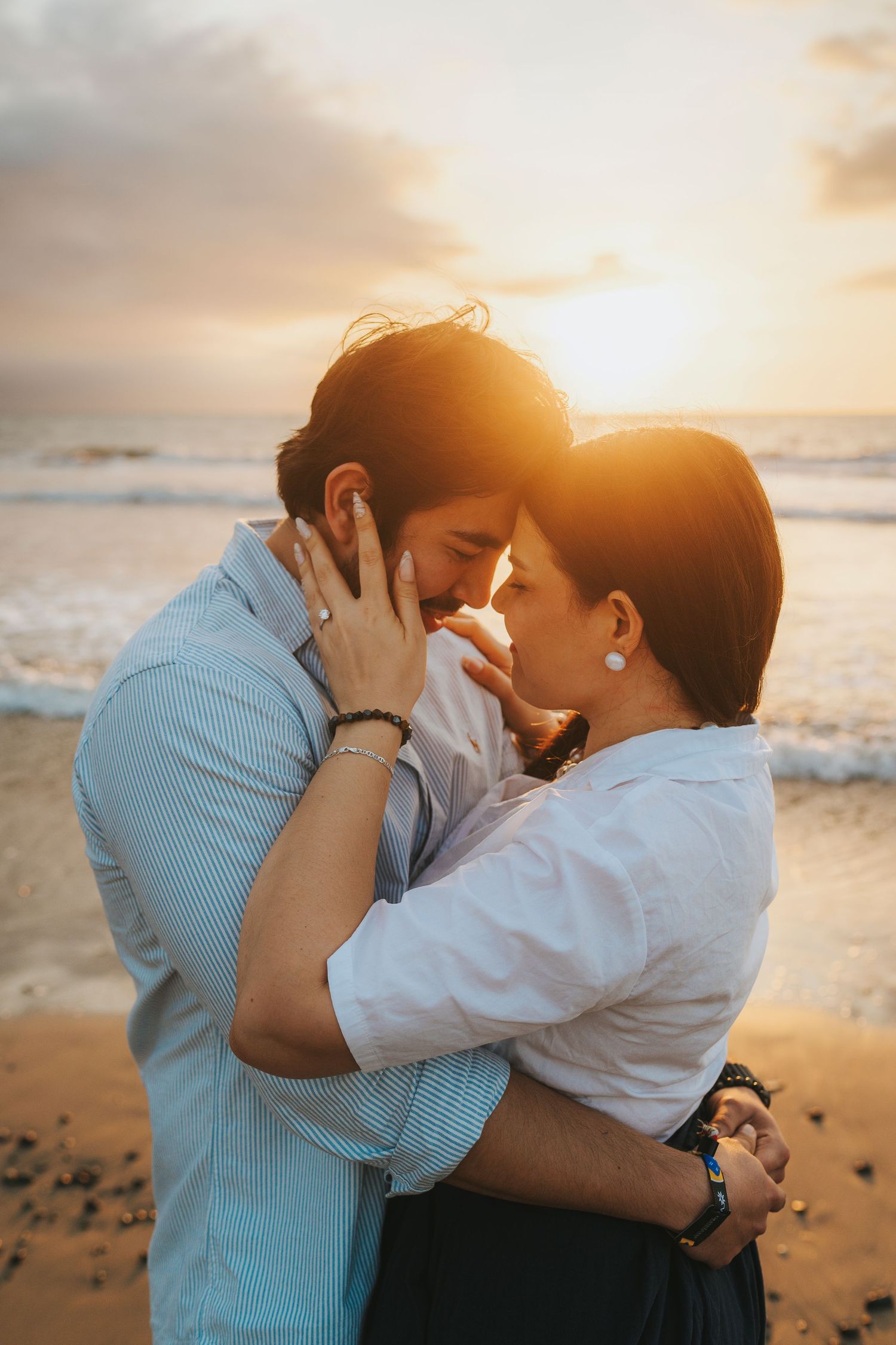 Romantic sunset beach photoshoot with warm golden lighting and ocean waves in background.