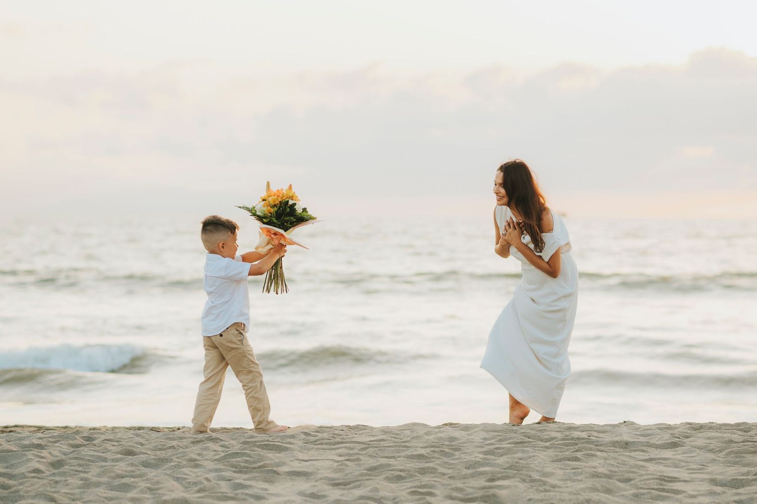 People in white clothing playing and running along a peaceful beach shoreline.