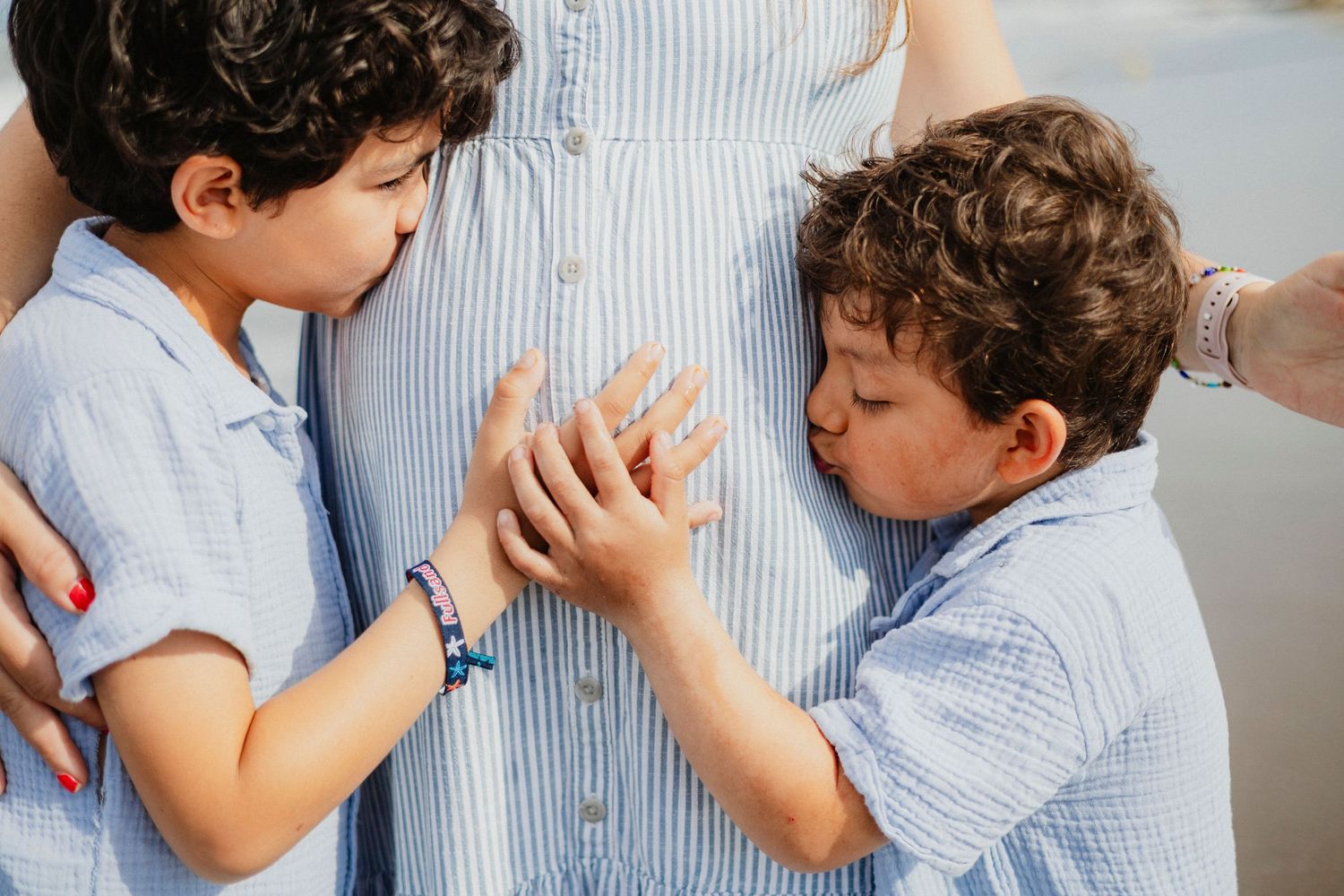 Two children in blue shirts playing a hand game while standing.
