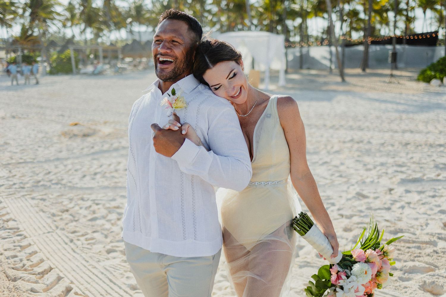 Joyful couple celebrating on a sunny beach with palm trees.