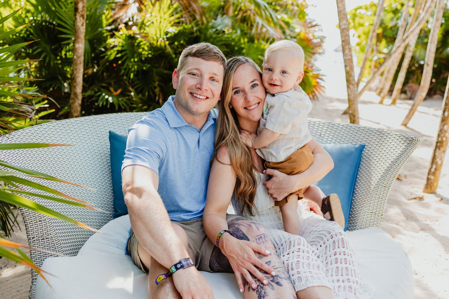 Family relaxing together on outdoor patio furniture in tropical setting.