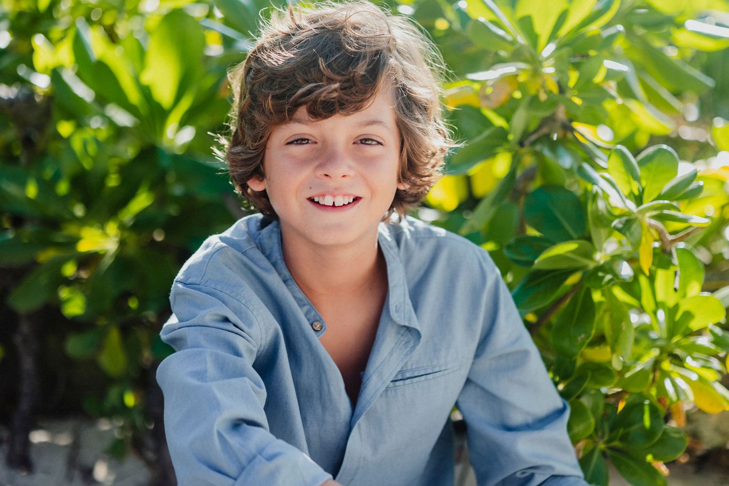 A casual portrait session in front of lush green foliage.