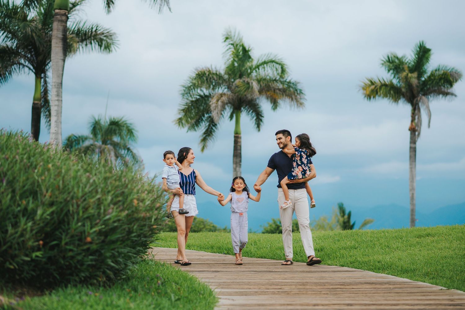 Family enjoying a walk together on a palm tree-lined path.