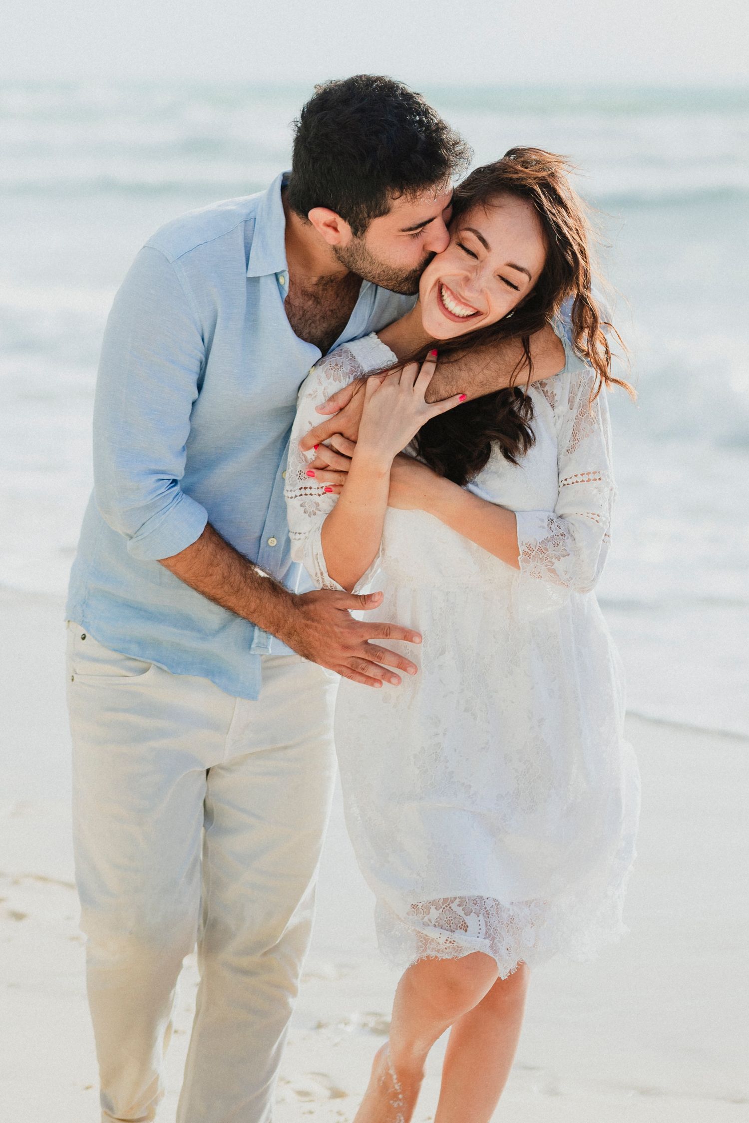 Romantic couple moment captured on white sandy beach.