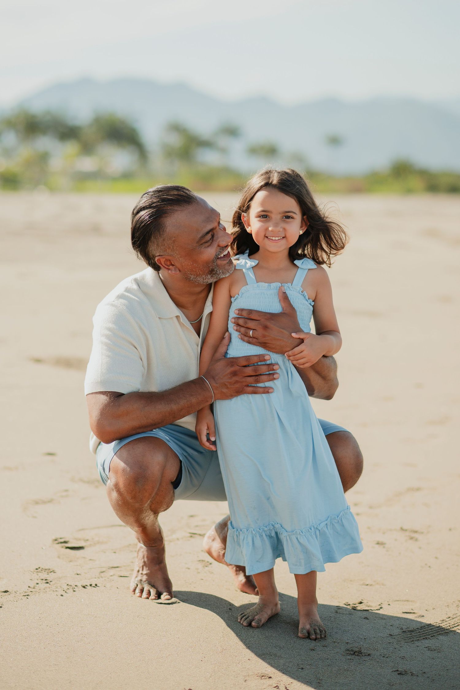 Heartwarming moments captured on a sandy beach with beautiful mountains in the background.