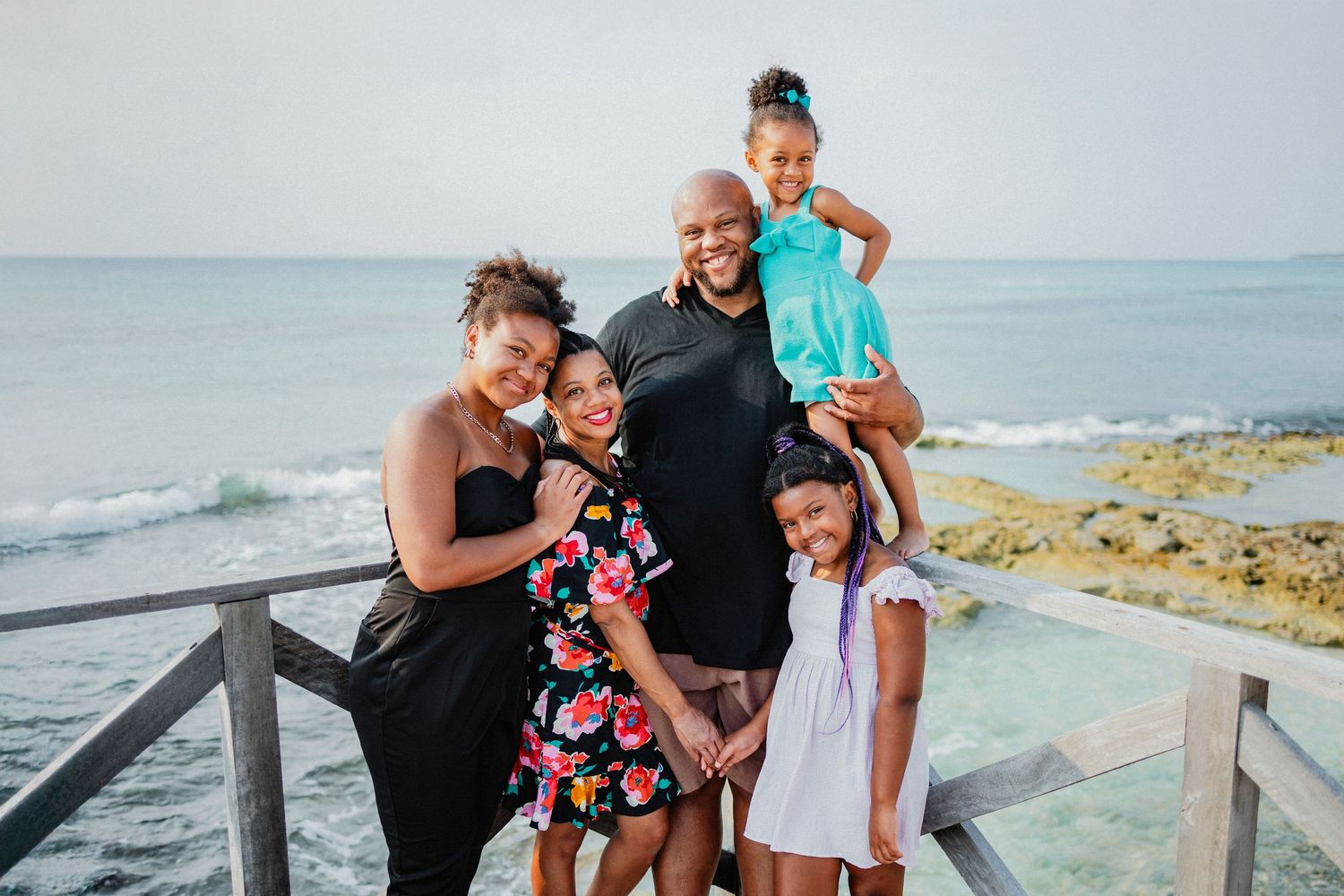 Family enjoys playful moments together on coastal boardwalk by ocean.