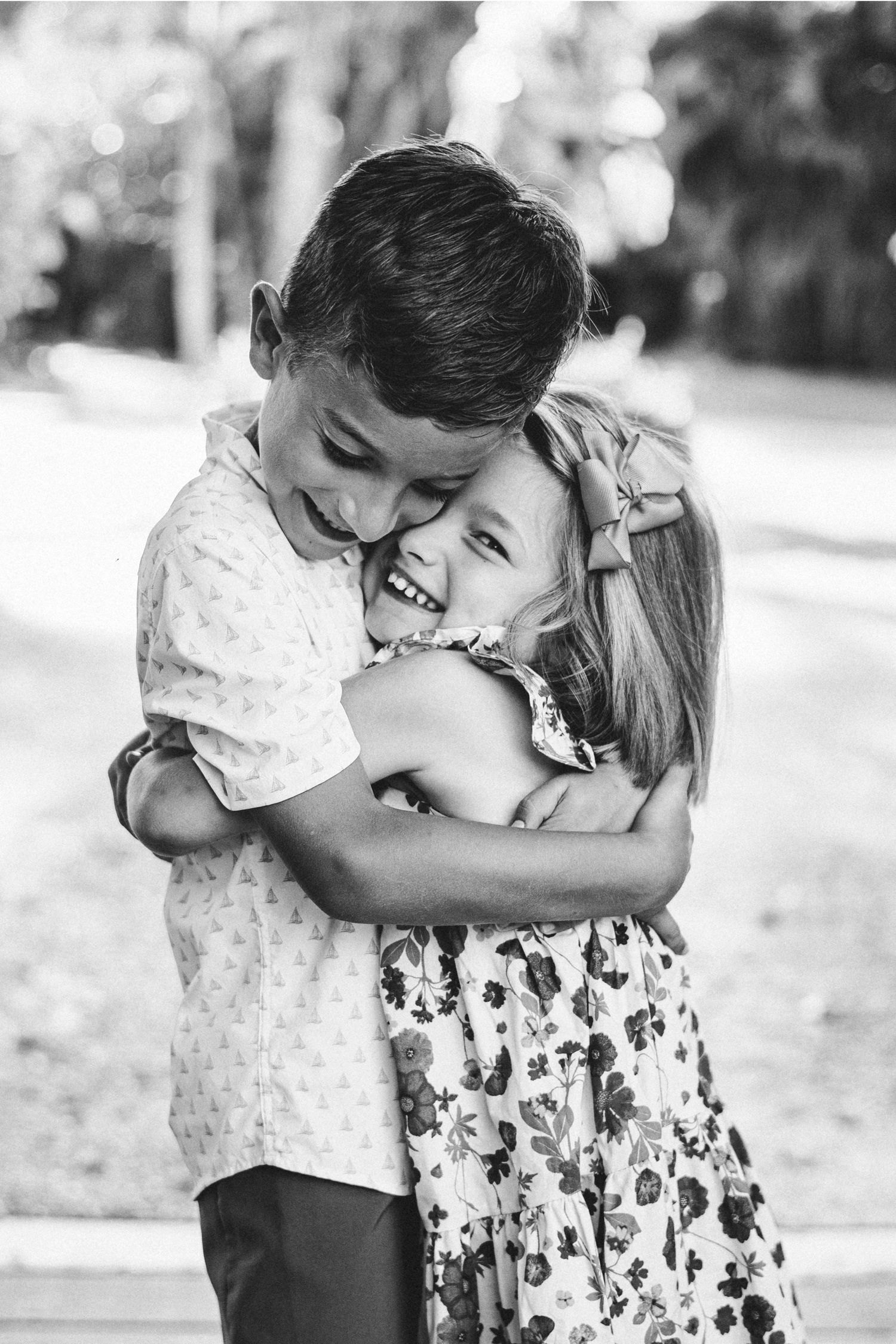 Children sharing playful moments together on a bench in black and white photography series.
