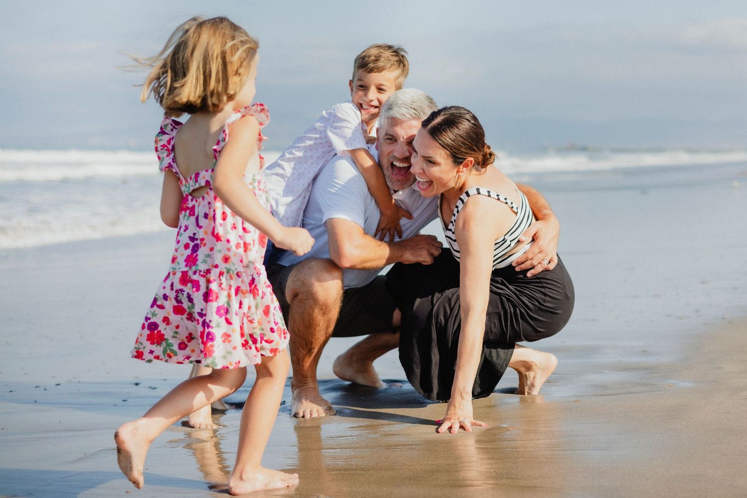 Family playing together and exploring at the beach during a sunny day.